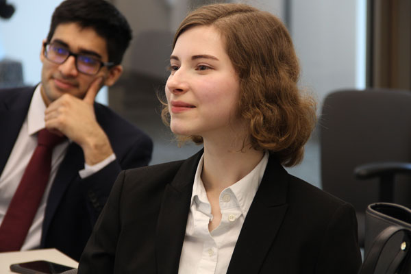 A student in the UT Dallas Professional Program in Finance listens to a presentation in professional attire.